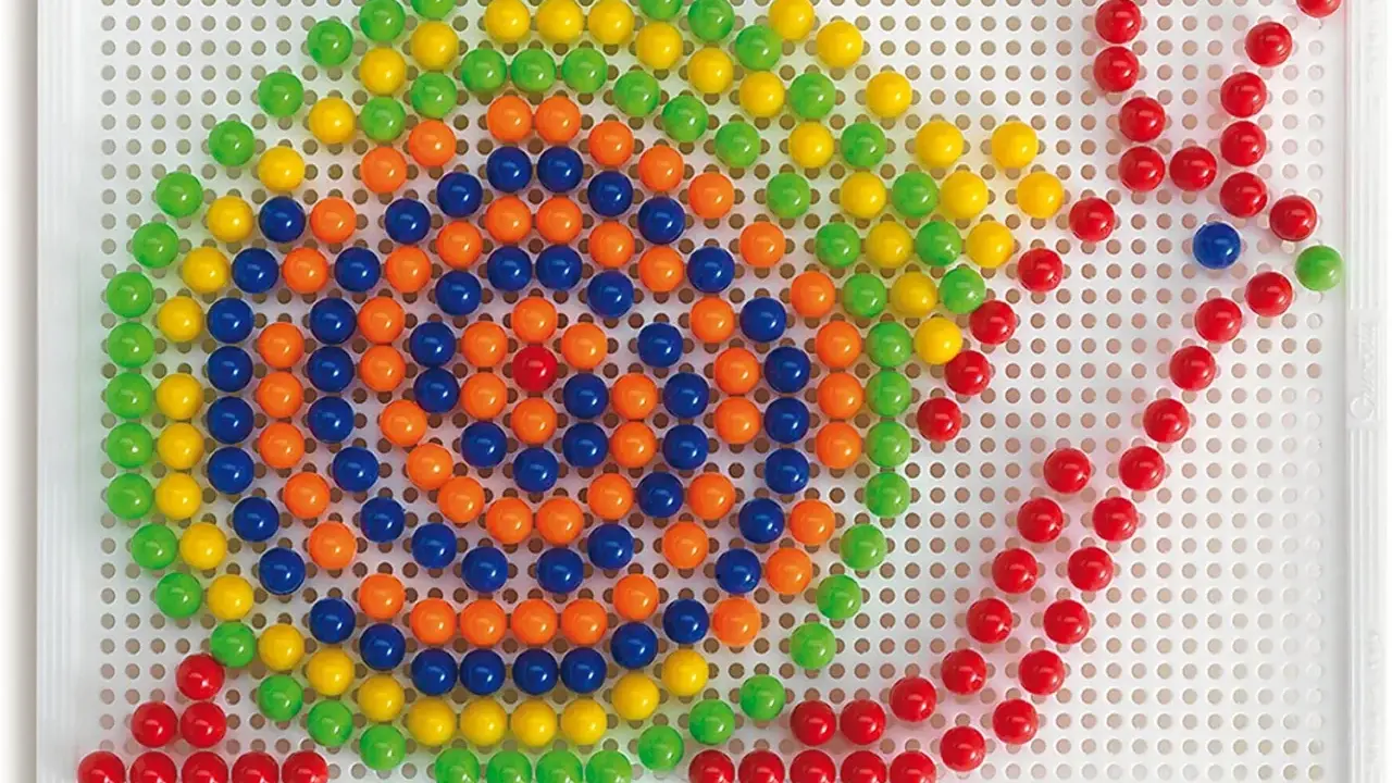Schemi chiodini gioco: un mosaico colorato di palline verdi, gialle, arancioni e blu su una base bianca, che forma un disegno astratto.