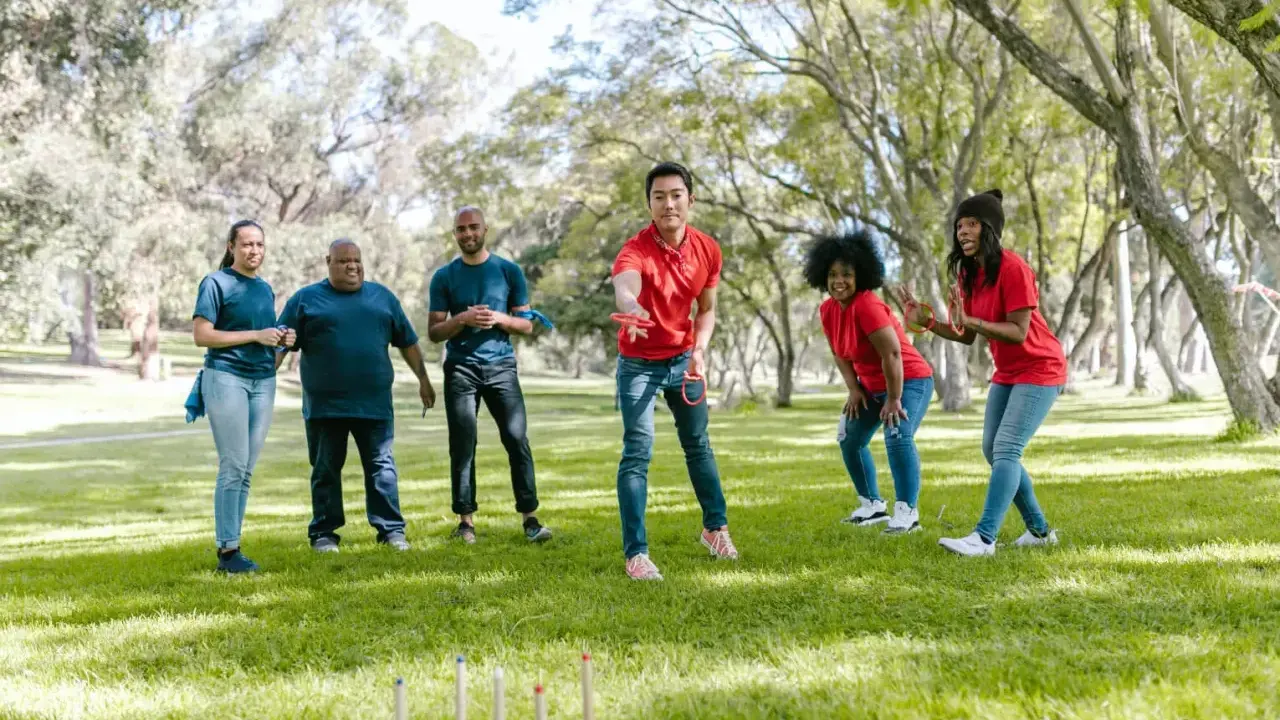 Un gruppo di amici si diverte con i giochi di una volta all'aperto, lanciando anelli in un parco soleggiato.