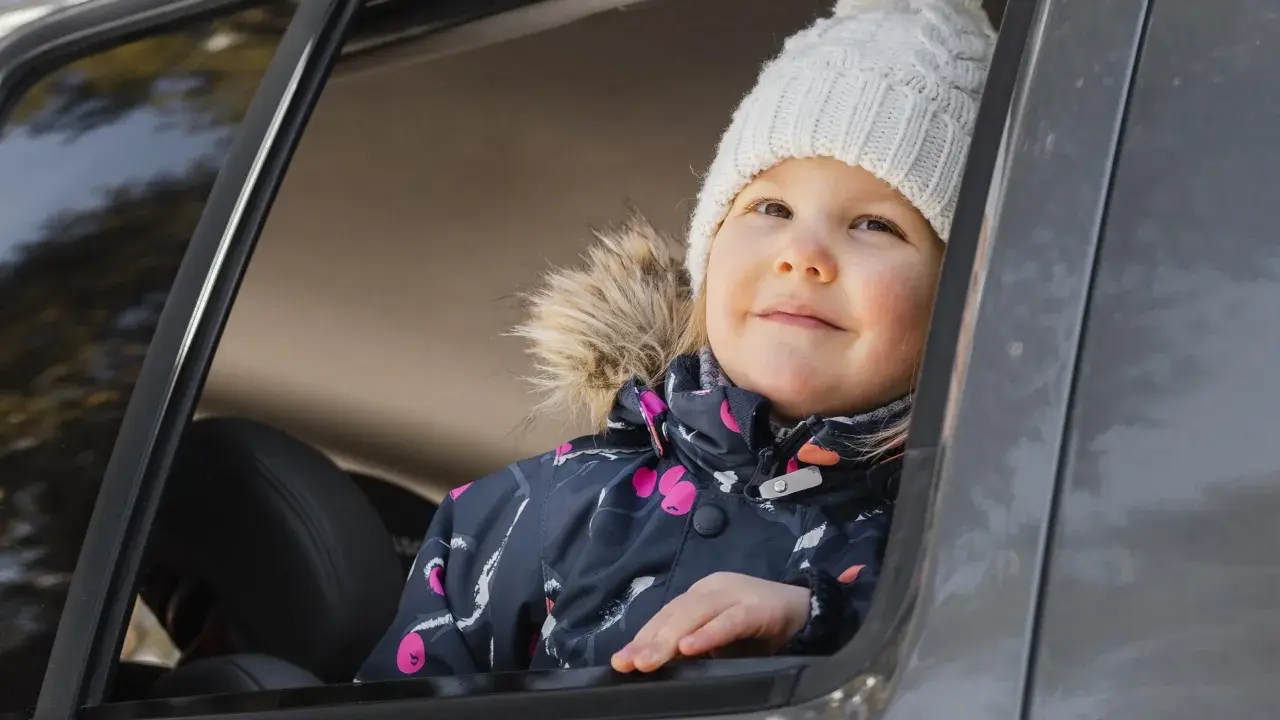 Bambina con cappellino bianco guarda fuori dal finestrino, pronta per i giochi da fare in macchina bambini.