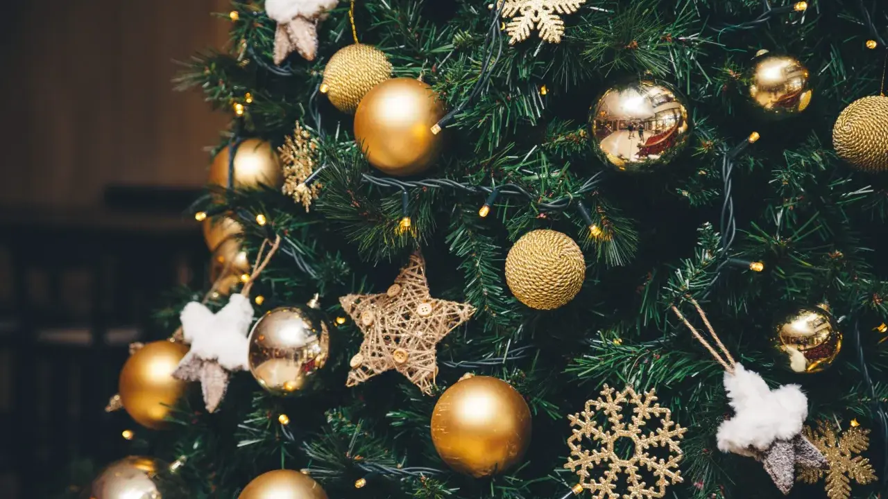 Un albero di Natale addobbato con palline dorate, fiocchi di neve scintillanti e stelle di stoffa. Le luci gialle creano un'atmosfera magica, un vero simbolo albero di natale.