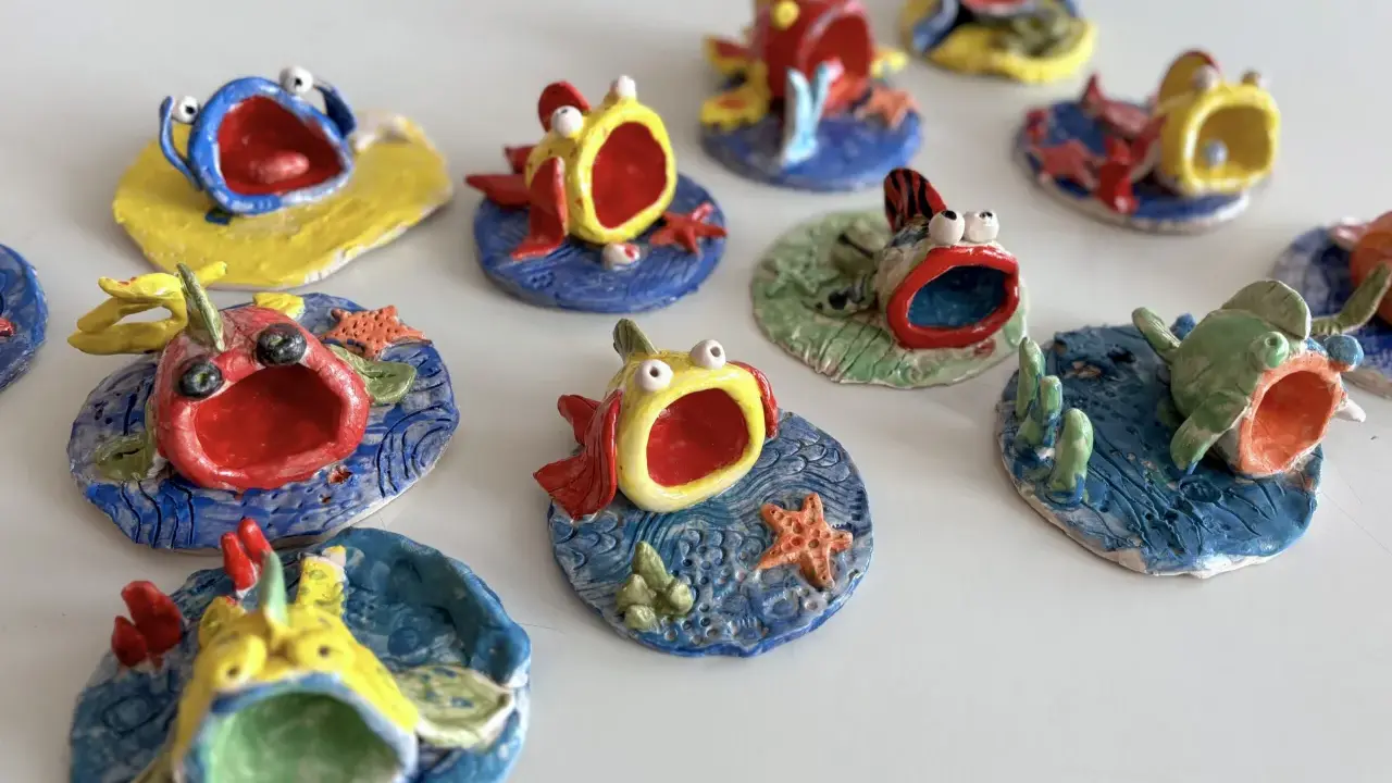 Piccoli pesci colorati, realizzati con la creta, con bocche spalancate e occhi sporgenti, sembrano nuotare in un mare di ceramica.