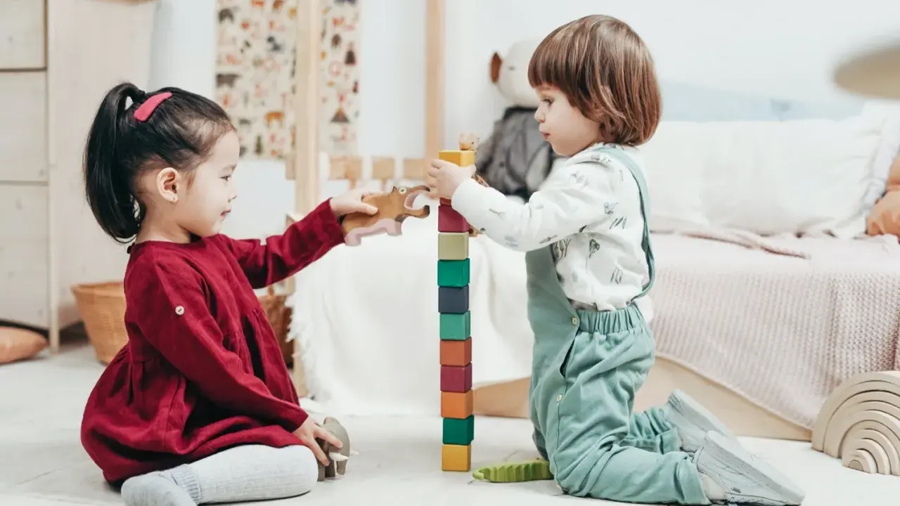 Bambini di 4 anni giocano con blocchi colorati e animali di legno, un'attività divertente e creativa.