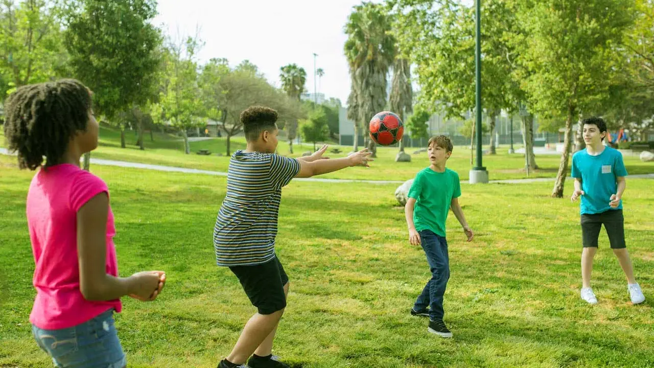 Bambini giocano a pallone in un parco, perfetti giochi per l'estate.