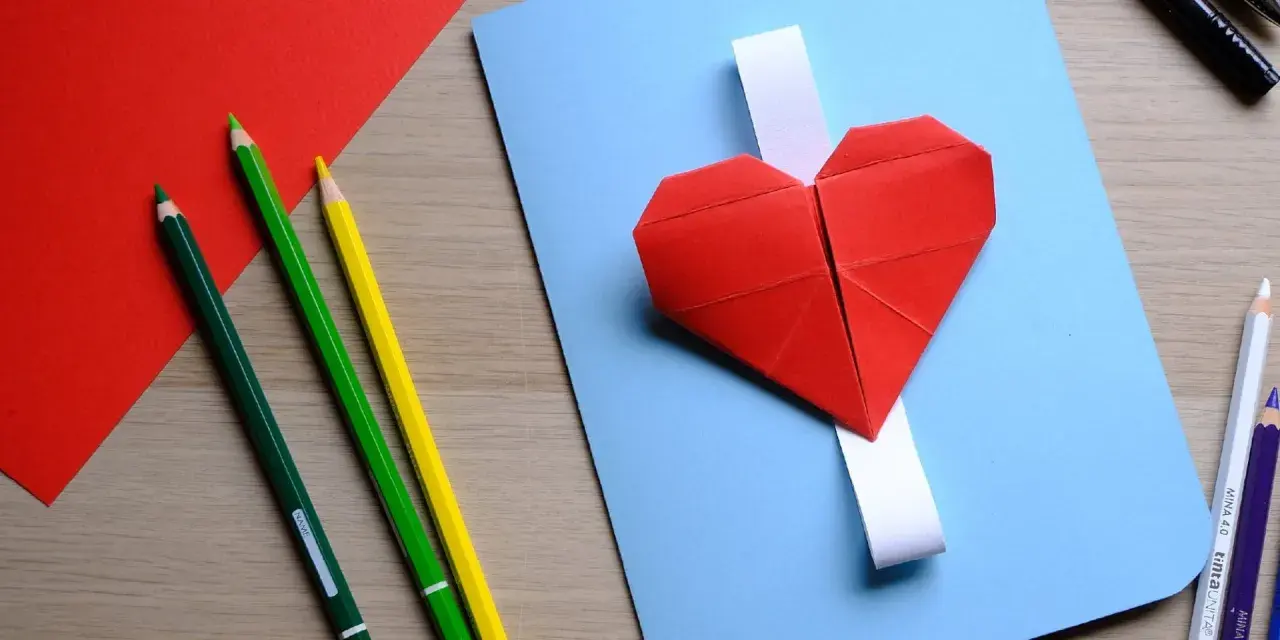 Cuori di carta rossi e matite colorate, pronti per un lavoretto per la festa dei nonni.