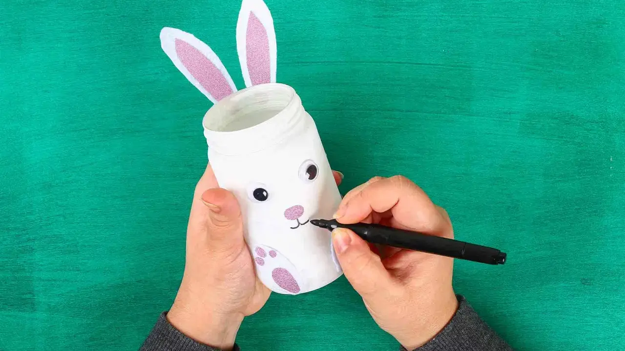 Mani creano un coniglietto pasquale con un barattolo, uno dei lavoretti di Pasqua bellissimi.