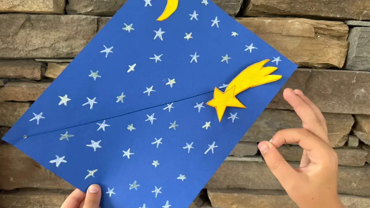 Un cielo blu con stelle e luna, una stella cometa gialla. Un lavoretto per bambini, stella di natale.