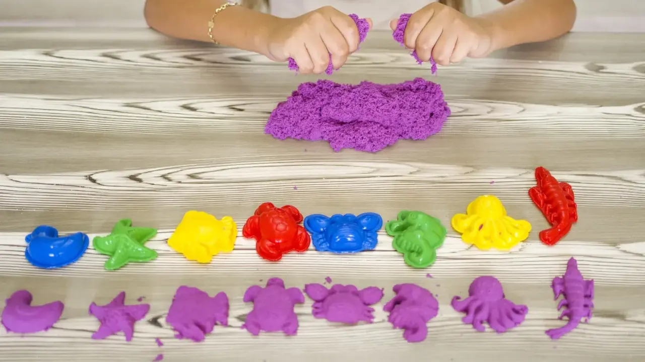 Bambina gioca con sabbia cinetica da che età? Formine marine colorate e viola, un divertimento sensoriale per tutti.
