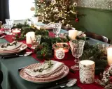 Ecco come preparare la tavola di Natale: piatti eleganti, candele profumate, rami di pino e lucine scintillanti creano un'atmosfera magica.