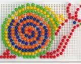 Schemi chiodini gioco: un mosaico colorato di palline verdi, gialle, arancioni e blu su una base bianca, che forma un disegno astratto.