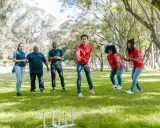 Un gruppo di amici si diverte con i giochi di una volta all'aperto, lanciando anelli in un parco soleggiato.