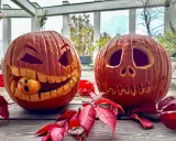 Due zucche intagliate per Halloween, una con una piccola arancia che fa la faccia spaventata. Un perfetto esempio di zucca halloween fai da te.