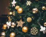 Un albero di Natale addobbato con palline dorate, fiocchi di neve scintillanti e stelle di stoffa. Le luci gialle creano un'atmosfera magica, un vero simbolo albero di natale.