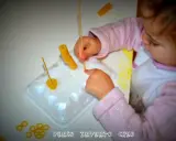Bambina di 3 anni si diverte con giochi creativi: infila pasta su stecchini, sviluppando manualità e fantasia.