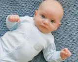 Un neonato con occhi azzurri e un pigiamino a pois, un riflesso di moro autismo nella sua innocenza.