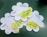 Lavoretto festa della donna infanzia: tre fiori di carta con mimose dipinte e fiocchi gialli. Scritte "Auguri!" e "8 Marzo Festa della Donna".