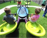 Bambini giocano su giostra inclusiva, pensata per giochi per bambini autistici non verbali.