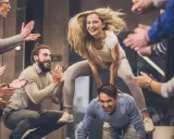 Un gruppo di amici si diverte con giochi da fare in gruppo seduti senza niente, una donna salta su un uomo mentre gli altri applaudono.