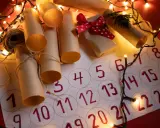 Un **calendario avvento fai da te cartoncino** con rotoli di carta marrone legati con spago, luci natalizie e un piccolo pacchetto regalo.