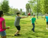 Bambini giocano a pallone in un parco, perfetti giochi per l'estate.