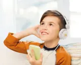 Ragazzo con cuffie bianche ascolta audio fiabe dal suo telefono, immerso in un mondo di storie.