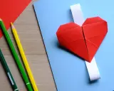Cuori di carta rossi e matite colorate, pronti per un lavoretto per la festa dei nonni.