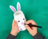 Mani creano un coniglietto pasquale con un barattolo, uno dei lavoretti di Pasqua bellissimi.