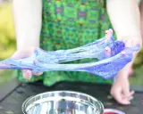 Mani che creano slime glitterato viola, un divertente esperimento su come si fa lo slime.