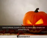 Zucca di Halloween illuminata, con foglie rosse e una citazione: "L'aria è bollente, la notte è scura, la danza della streghe non porterà fortuna." Perfetta per frasi di Halloween per bambini.
