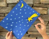 Un cielo blu con stelle e luna, una stella cometa gialla. Un lavoretto per bambini, stella di natale.