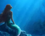 La sirenetta storia breve: una giovane sirena dai capelli rossi guarda verso l'alto, sognando il mondo di sopra, seduta su una roccia sottomarina.