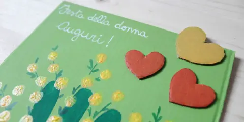 Biglietto fai da te per la Festa della Donna con mimose dipinte e cuori. Idee creative per un augurio speciale.
