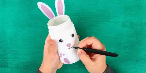 Mani creano un coniglietto pasquale con un barattolo, uno dei lavoretti di Pasqua bellissimi.