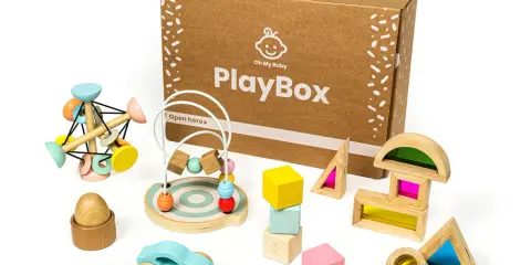 Scatola PlayBox con giochi di precisione in legno: macchinina, abaco, blocchi colorati e forme trasparenti per stimolare la creatività.