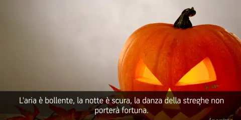 Zucca di Halloween illuminata, con foglie rosse e una citazione: "L'aria è bollente, la notte è scura, la danza della streghe non porterà fortuna." Perfetta per frasi di Halloween per bambini.