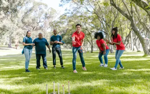 Un gruppo di amici si diverte con i giochi di una volta all'aperto, lanciando anelli in un parco soleggiato.