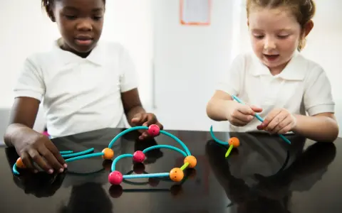 Bambini impegnati in attività sensoriali, costruendo con forme colorate.