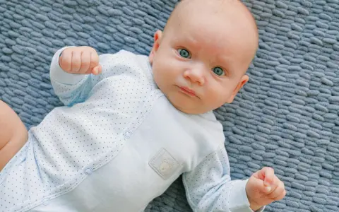 Un neonato con occhi azzurri e un pigiamino a pois, un riflesso di moro autismo nella sua innocenza.