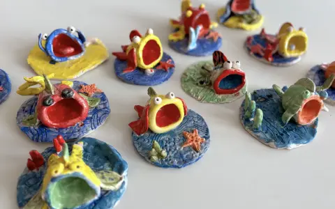 Piccoli pesci colorati, realizzati con la creta, con bocche spalancate e occhi sporgenti, sembrano nuotare in un mare di ceramica.