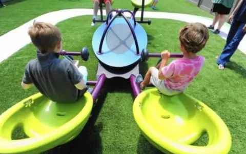 Bambini giocano su giostra inclusiva, pensata per giochi per bambini autistici non verbali.
