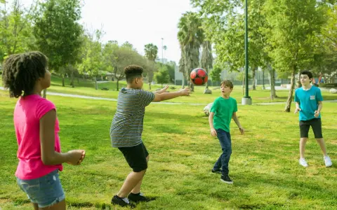 Bambini giocano a pallone in un parco, perfetti giochi per l'estate.
