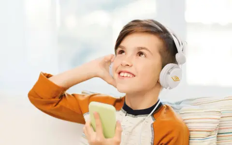 Ragazzo con cuffie bianche ascolta audio fiabe dal suo telefono, immerso in un mondo di storie.