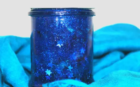 Barattolo della calma fai da te con glitter blu e stelline, un piccolo universo scintillante per rilassarsi.