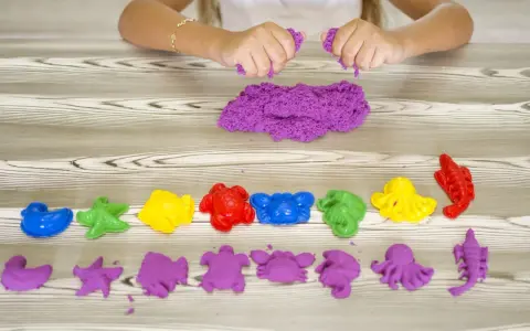 Bambina gioca con sabbia cinetica da che età? Formine marine colorate e viola, un divertimento sensoriale per tutti.