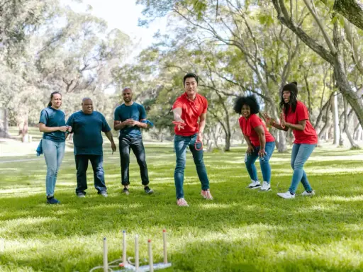 Un gruppo di amici si diverte con i giochi di una volta all'aperto, lanciando anelli in un parco soleggiato.