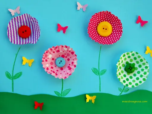 Lavoretti primavera: fiori colorati con bottoni e farfalle di carta su sfondo azzurro.