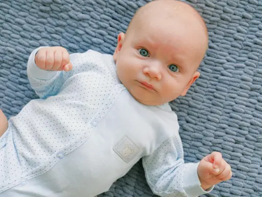 Un neonato con occhi azzurri e un pigiamino a pois, un riflesso di moro autismo nella sua innocenza.