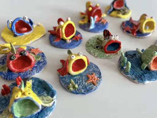 Piccoli pesci colorati, realizzati con la creta, con bocche spalancate e occhi sporgenti, sembrano nuotare in un mare di ceramica.