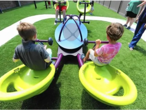 Bambini giocano su giostra inclusiva, pensata per giochi per bambini autistici non verbali.