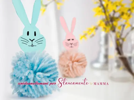 Coniglietti con pompon di lana e teste di coniglio origami. Uno è azzurro, l'altro rosa, con fiori gialli sullo sfondo.