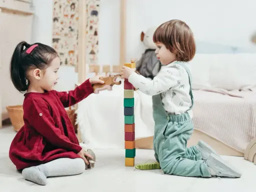 Bambini di 4 anni giocano con blocchi colorati e animali di legno, un'attività divertente e creativa.